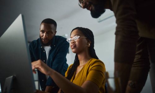 A motivated entrepreneurs working tirelessly at a desktop computer, showcasing their dedication to success. Their focused expressions and engaged body language convey their commitment to accomplishing their goals even during late hours.